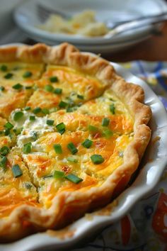 a quiche with cheese and green onions on a plate