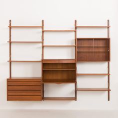 a wall mounted shelf unit with drawers and shelves on each side, against a white wall