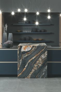 a marble counter top in a kitchen with lights above it and shelves on the wall