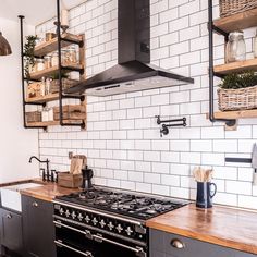 a stove top oven sitting inside of a kitchen next to wooden shelves filled with pots and pans