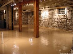 an empty room with exposed ceiling and stone walls