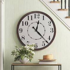 a clock on the wall above a table with flowers