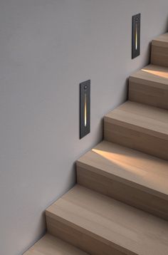 two lights are on the wall above some stairs