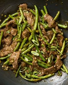 meat and green beans in a wok with seasoning on the side, ready to be eaten