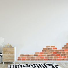 a room with a brick wall and wooden flooring in front of a white dresser