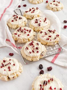 cookies with white icing and cranberries on a cooling rack next to a towel