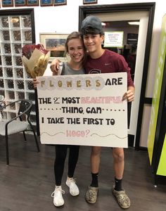 two young people standing next to each other holding a sign that says, flowers are the 2 most beautiful thing can i take the first to 1900?