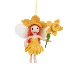 an ornament shaped like a fairy holding a flower and wearing a yellow dress