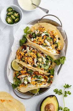 three tacos on a plate with avocado and salsa