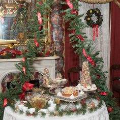 a table topped with cakes and desserts next to a fire place covered in christmas decorations