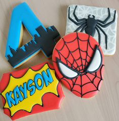 three decorated cookies with spiderman and name on them, sitting on a wooden table