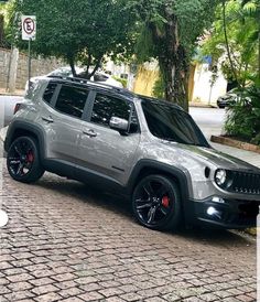 a grey jeep parked on the side of a road next to a street sign and trees