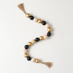 a beaded necklace with tassels and gold beads on it, sitting on a white surface