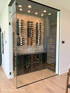 a wine cellar with glass walls and wooden flooring in the middle of a room