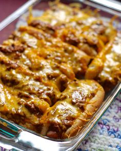 a casserole dish with meat and cheese in it on a colorful table cloth