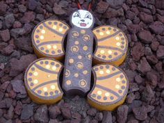 a butterfly shaped object sitting on top of some rocks next to gravel and stones with yellow dots