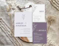 the wedding stationery is laid out on top of a white table cloth with dried flowers