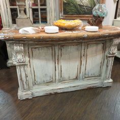 an old wooden table with plates and bowls on it in a room filled with furniture