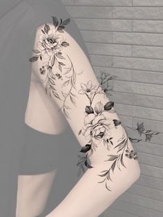 a woman's arm with flowers and leaves tattooed on the side of her body