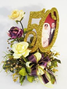 a 50th birthday cake topper with flowers and ribbon around it on a white background