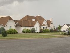 a row of white houses sitting on the side of a road next to a lush green field