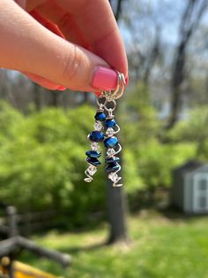 a person holding onto some kind of blue and silver beaded necklace in their hand