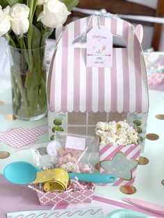 a pink and white table topped with lots of food next to a vase filled with flowers