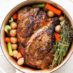 a pot filled with meat, potatoes and carrots on top of a white table