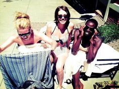 three women in bathing suits sitting next to each other on a toweled bench and smiling at the camera