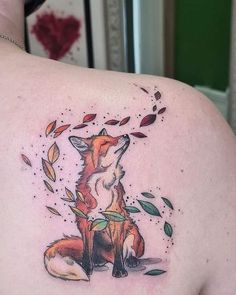 a woman's back with a tattoo of a fox and leaves