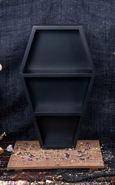 a black shelf sitting on top of a wooden stand next to a blue wall and carpet