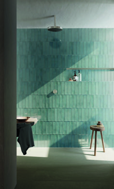 a green tiled wall in a bathroom with stools