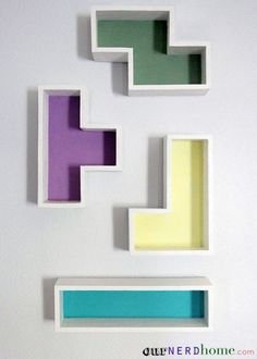 three shelves with different colors and shapes on the wall, one has a shelf for books