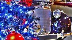 an old car is decorated with blue and red christmas lights, ornaments and baubles