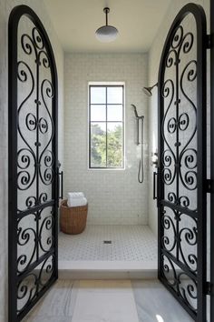 an open door leading to a bathroom with white tile and black wrought ironwork on the walls