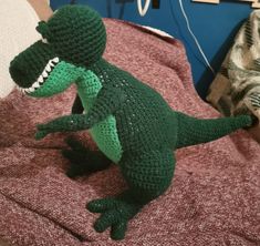 a crocheted dinosaur toy sitting on top of a bed