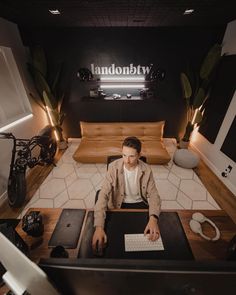 a man sitting at a desk in front of a computer on top of a wooden table