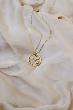 A gold rotating necklace which features the face of the sun on one side and the face of the moon on the other. Comes in 2 sizes. Small charm is 1” wide and hangs from a 16” chain Big charm is 1.5” wide and hangs from a 21” chain Silver Sun And Moon Design Gold-plated Necklace, Moon Phase Medallion Necklace In Amulet Style, Moon Phase Medallion Necklaces Styled As Amulets, Celestial Medallion Necklace With Moon Charm, Celestial Moon Phase Medallion Necklace, Brass Moon Charm Round Pendant Necklace, Gold Moon Phase Amulet Jewelry, Celestial Round Locket Necklace, Celestial Brass Necklace With Sun And Moon Design