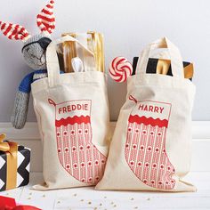 two canvas bags with personalized christmas stockings on them and candy canes in the bag