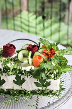 a cake with cucumbers, carrots and herbs on it