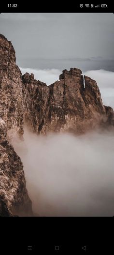 some very tall rocks in the sky with clouds around them and one rock sticking out of the ground