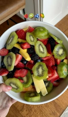 a white bowl filled with sliced up kiwis and strawberries on top of a wooden table