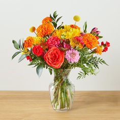 a vase filled with colorful flowers on top of a wooden table