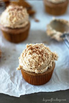 cupcakes with frosting and cinnamon sprinkles sitting on wax paper