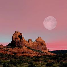 the full moon is setting over red rock formations