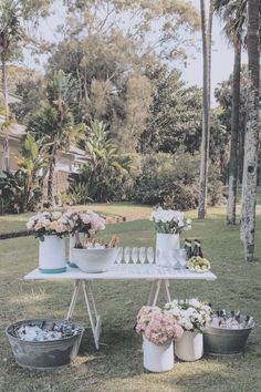 a table with flowers and drinks on it in front of some palm tree's