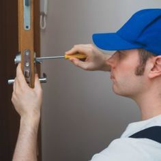 a man wearing a blue hat and holding a screwdriver in front of a door