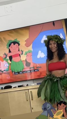 a woman in a hula skirt standing next to a large cartoon character on the wall