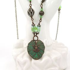 This is a handmade antique brass necklace featuring a lily pad pendant with a frog charm.  The pendant is accented with glass beads and rhinestone beads.  The necklace measures 24" in length.  The metal components are nickel and lead free. Green Lily, Necklace Green, Brass Necklace, Rhinestone Bead, Green Necklace, Lily Pads, Glass Bead, Beaded Chain, Antique Brass