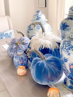 blue and white pumpkins are sitting on a table in front of large vases